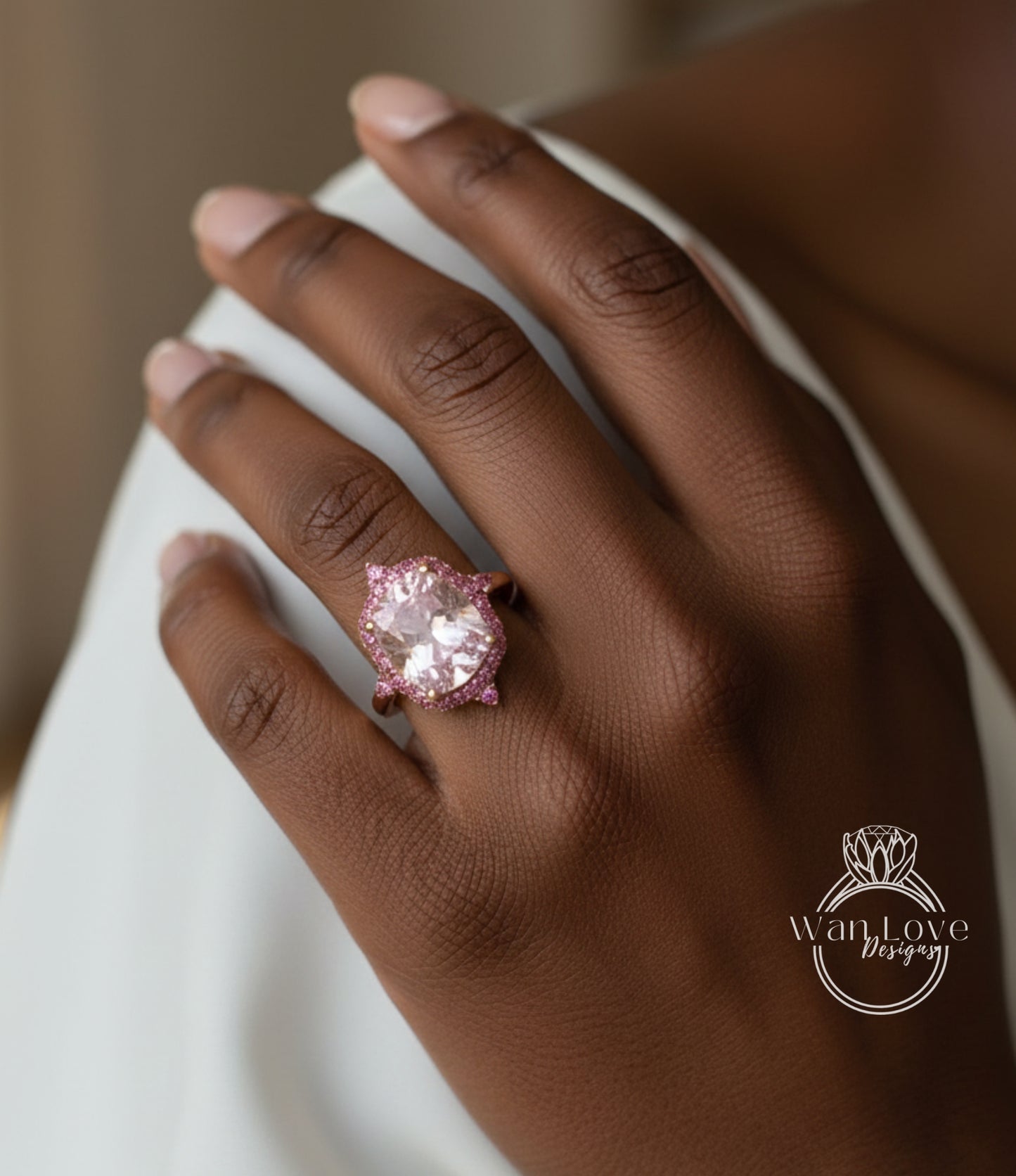 A close-up of a hand wearing a large, pink diamond ring with a halo of smaller pink diamonds.