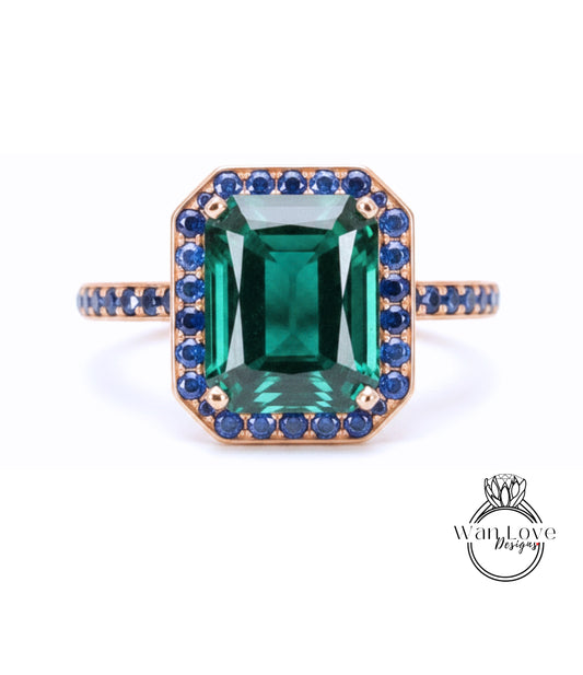 A large, rectangular green gemstone set in a gold ring with a blue gemstone border.