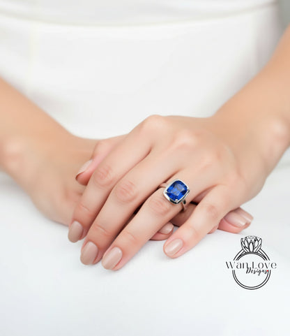 A close-up of a person's hand wearing a ring with a large blue gemstone.