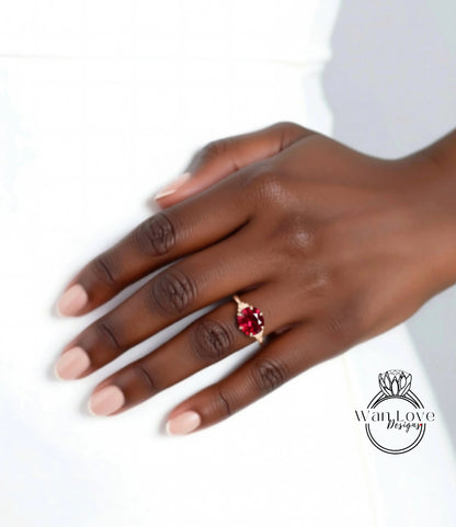 A close-up of a hand wearing a red gemstone ring against a white background.