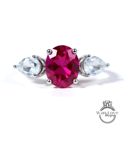 A ring with a large oval-shaped gemstone in the center, surrounded by two smaller pear-shaped gemstones on either side.