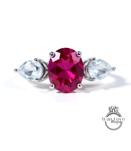 A ring with a large oval-shaped gemstone in the center, surrounded by two smaller pear-shaped gemstones on either side.