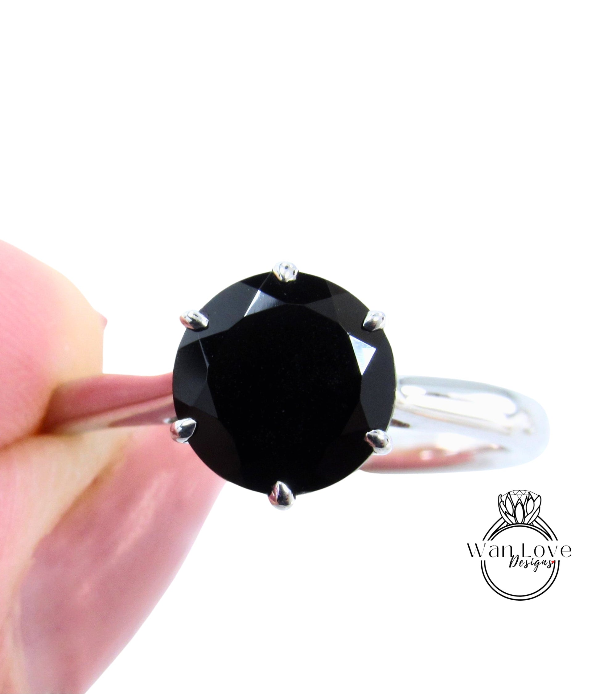 A close-up image of a person's hand holding a ring with a large, dark black diamond as the centerpiece.