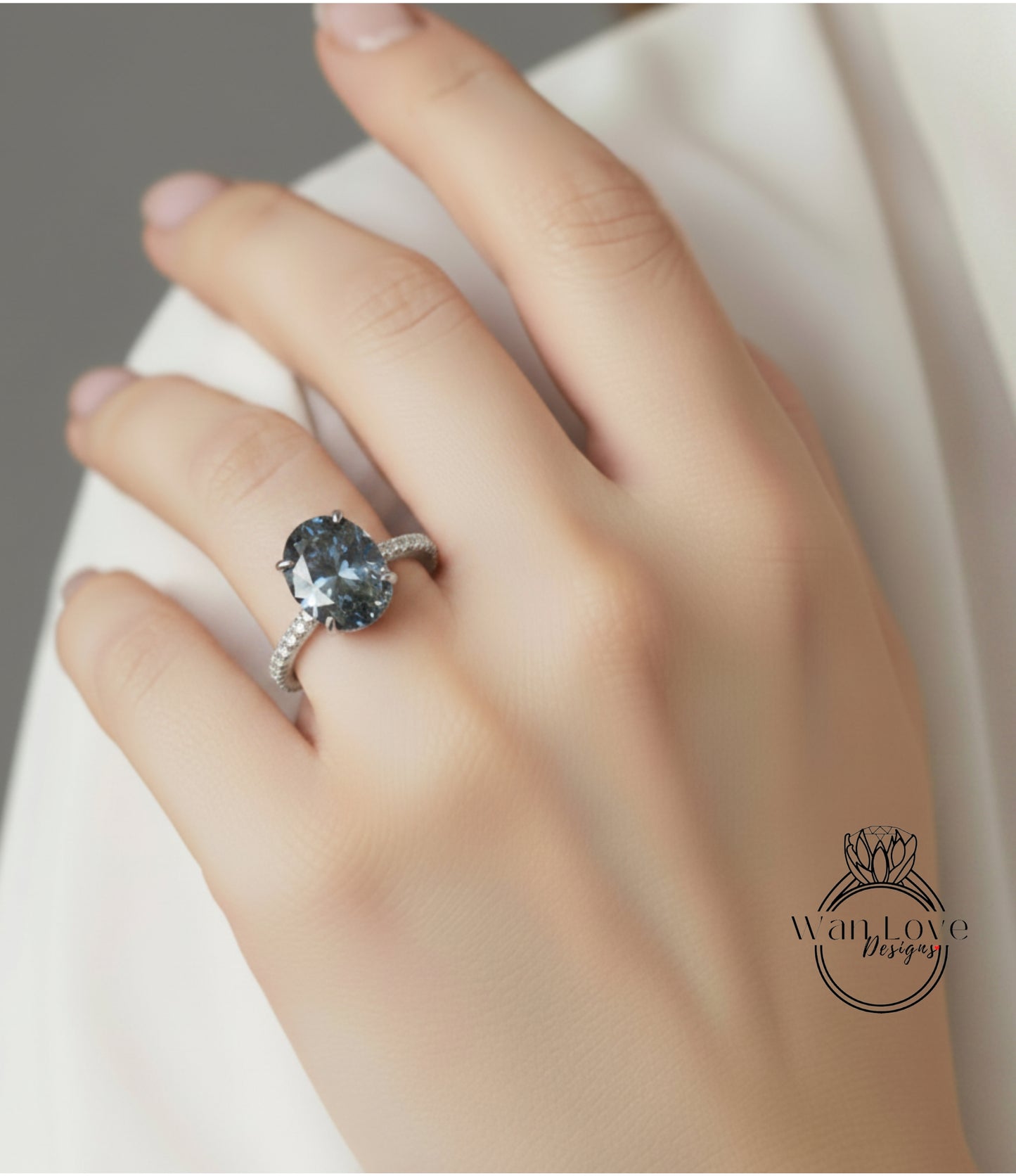 A close-up of a hand wearing a diamond ring with a large blue gemstone.