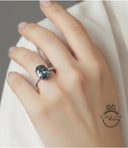 A close-up of a hand wearing a diamond ring with a large blue gemstone.