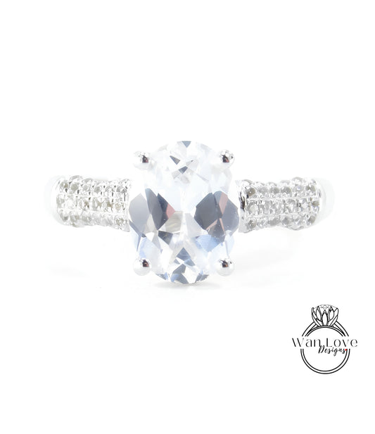A close-up view of a diamond engagement ring with a large oval-shaped gemstone set in a silver band.
