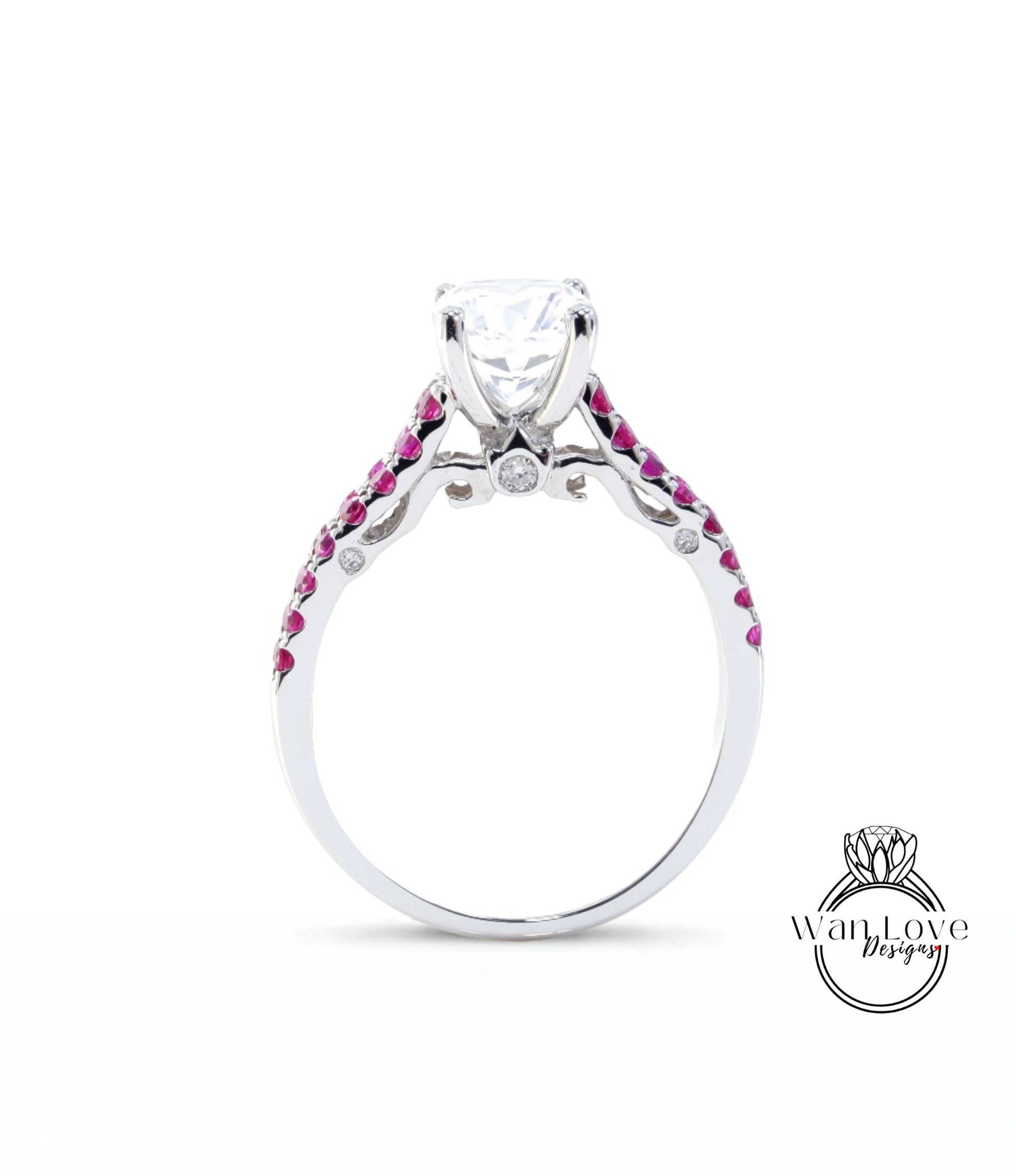 A silver engagement ring with a large central diamond and a row of smaller diamonds on either side, set in a silver band with red gemstones.