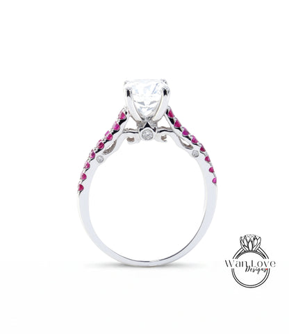 A silver engagement ring with a large central diamond and a row of smaller diamonds on either side, set in a silver band with red gemstones.
