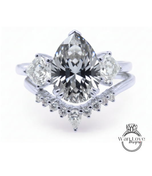 A stunning diamond engagement ring with a large pear-shaped diamond at the center, surrounded by smaller diamonds on either side. The ring is set in a silver band, and the background is a plain white color.