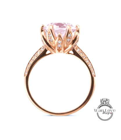 A gold ring with a large pink gemstone, possibly a diamond, set in a delicate flower-like design.