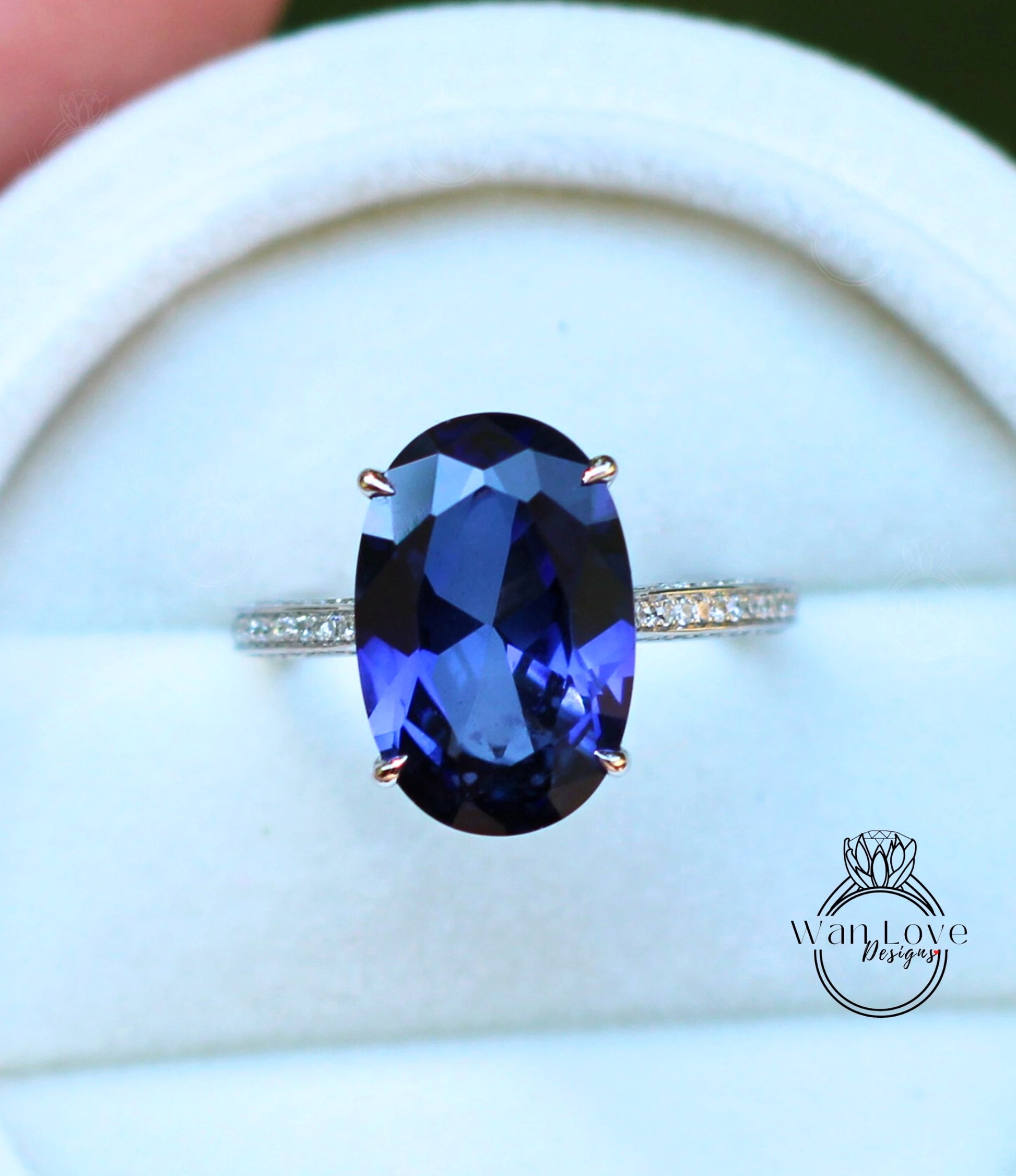 A close-up image of a ring with a large oval-shaped blue gemstone, possibly a sapphire, set in a silver band.