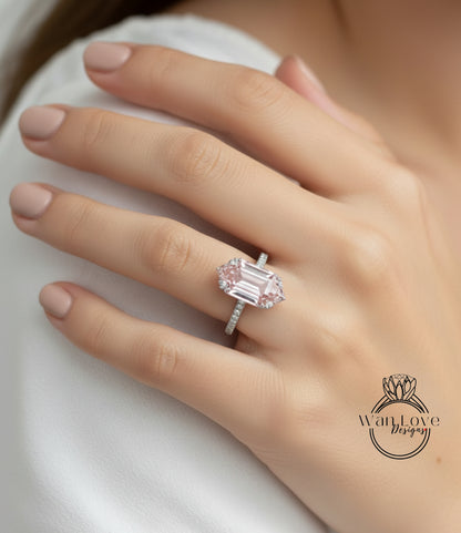 A close-up of a person's hand wearing a large, pink diamond engagement ring.