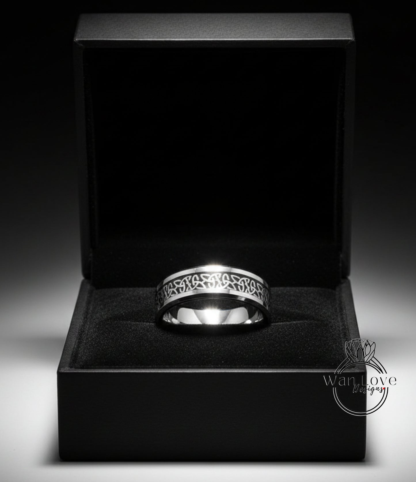 A silver ring is displayed in a black jewelry box against a dark background.