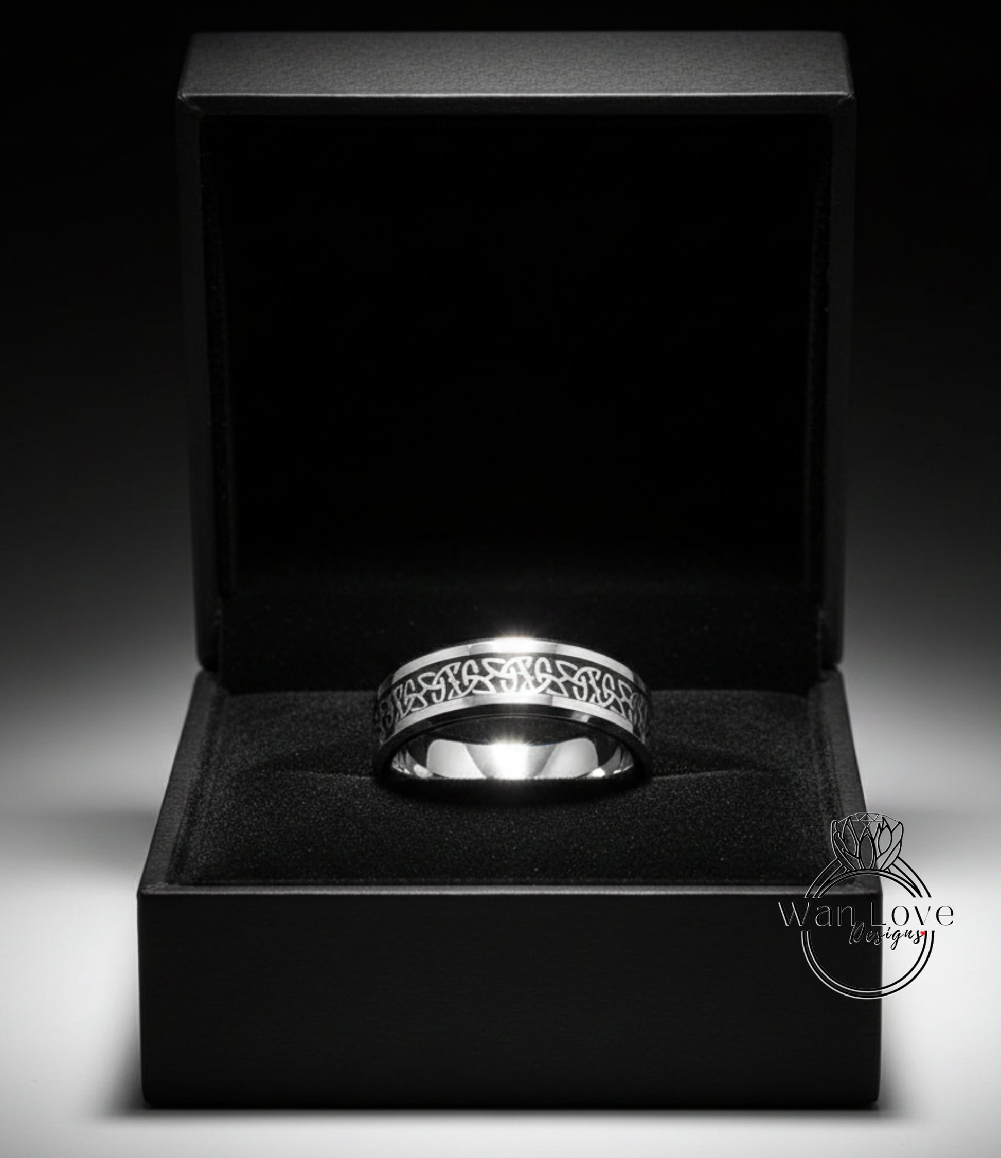 A silver ring is displayed in a black jewelry box against a dark background.