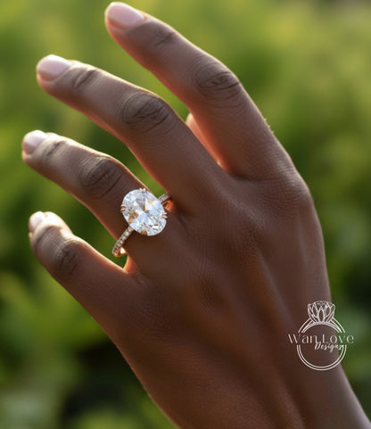 A close-up of a person's hand wearing a large, oval-shaped diamond engagement ring.