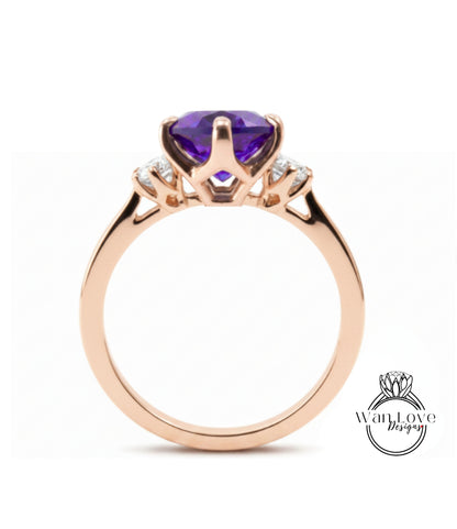 A gold ring with a large purple gemstone, likely an amethyst, set in a three-prong design.