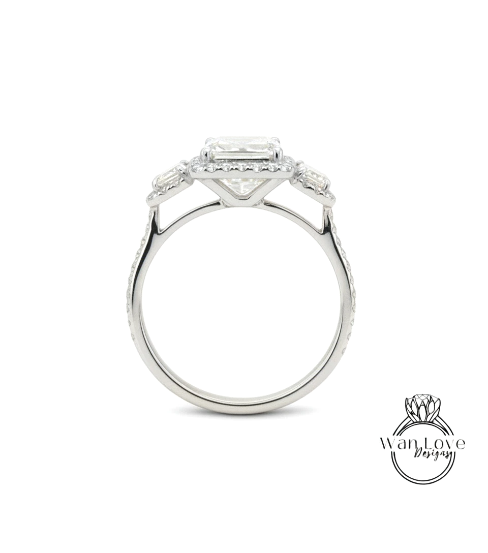 A silver engagement ring with a large central diamond surrounded by smaller diamonds on either side.