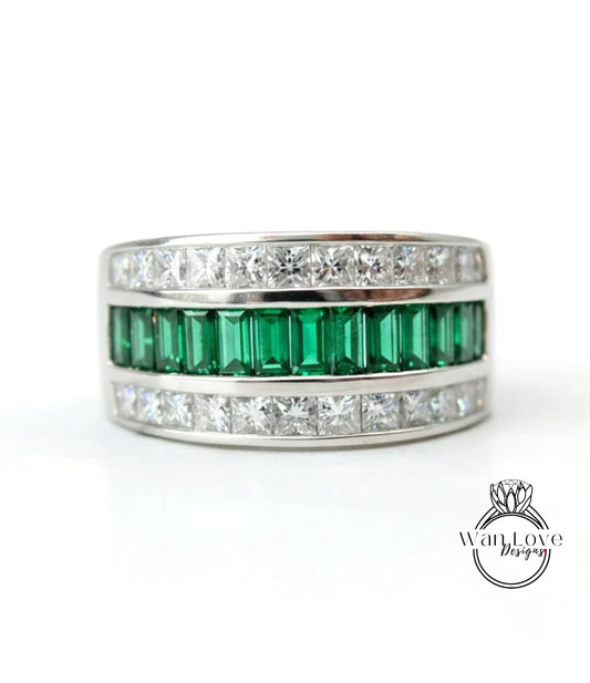 A silver ring with a row of green and white diamonds set in it.