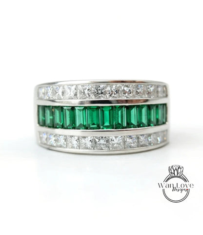 A silver ring with a row of green and white diamonds set in it.