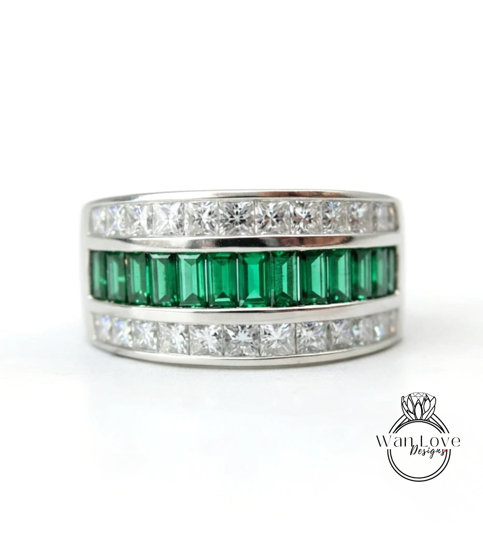 A silver ring with a row of green and white diamonds set in it.