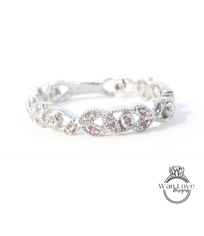 A silver ring with a decorative band adorned with small, round, purple gemstones.