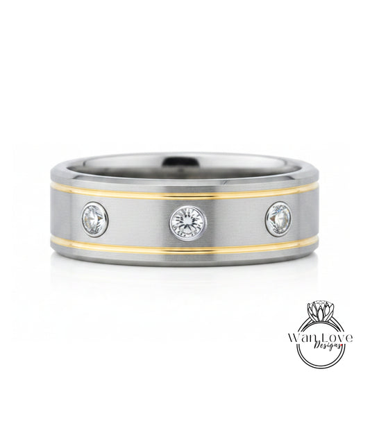 A silver and gold ring with three round diamonds set in the center.