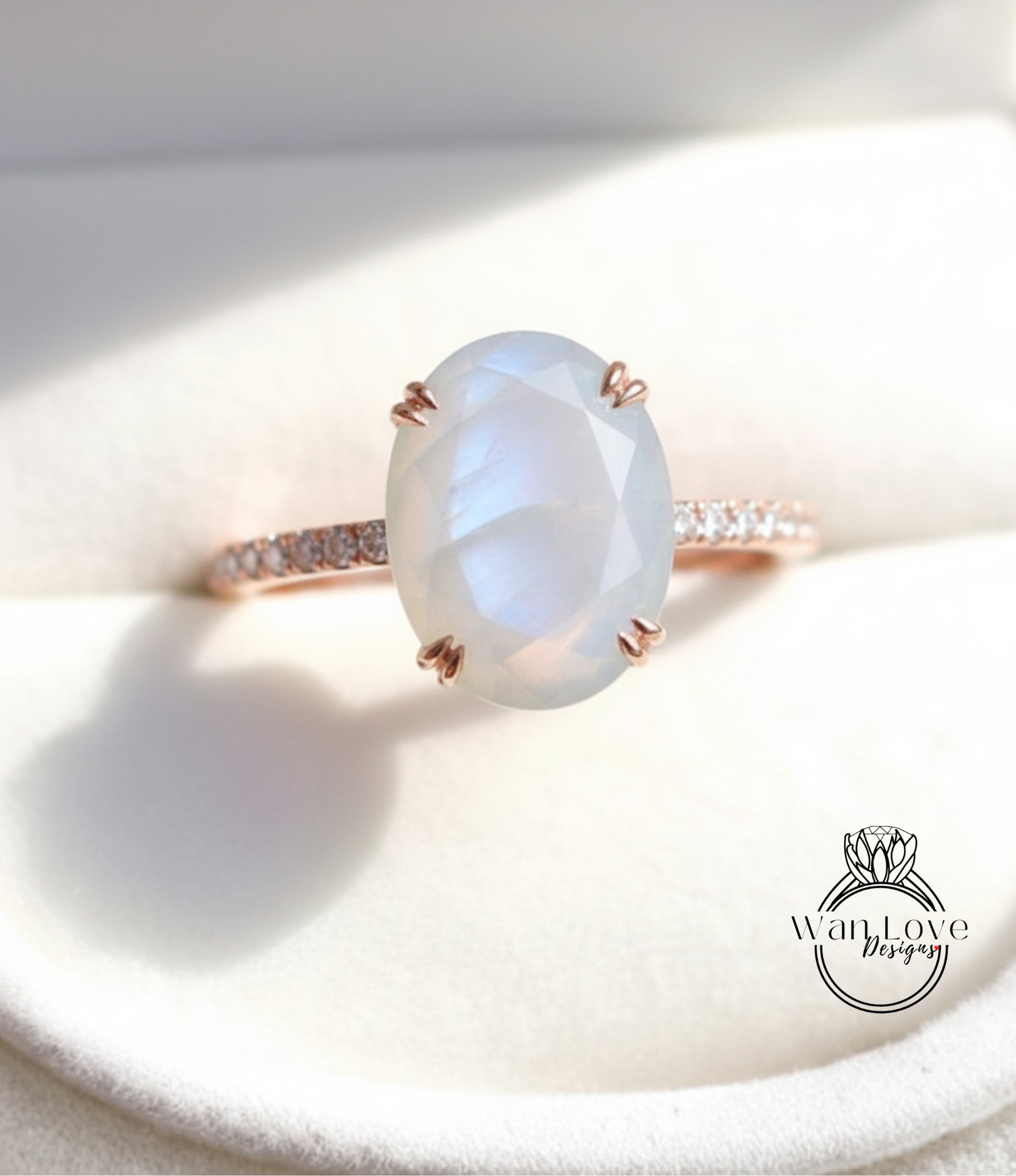 A close-up image of a rose gold ring with a large oval-shaped moonstone set in the center.