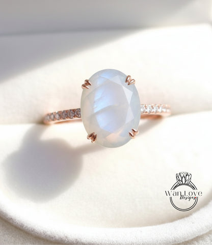 A close-up image of a rose gold ring with a large oval-shaped moonstone set in the center.