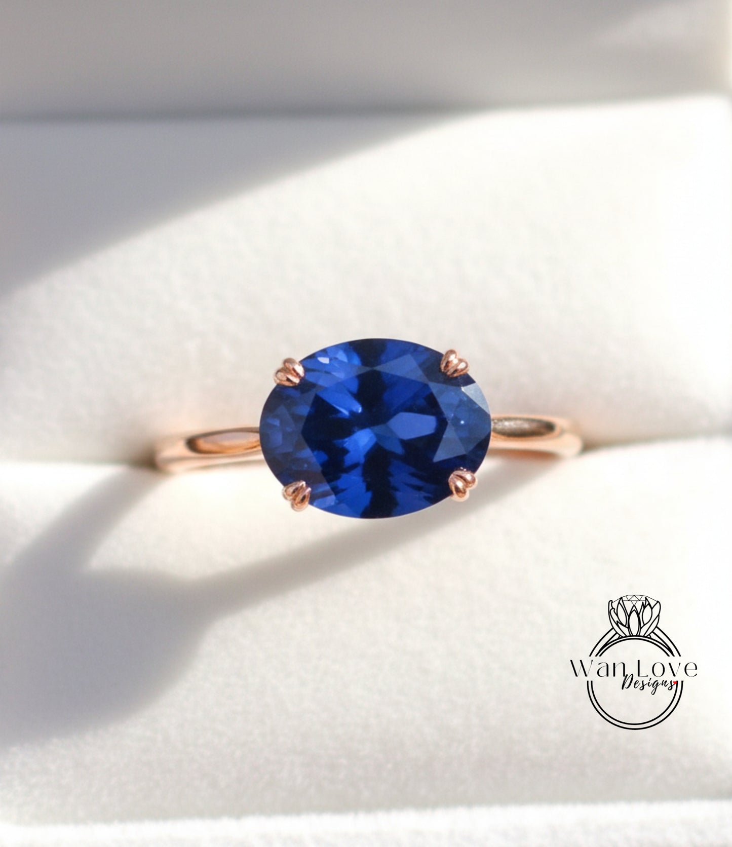 A close-up image of a gold ring with a large blue gemstone, placed on a white background.