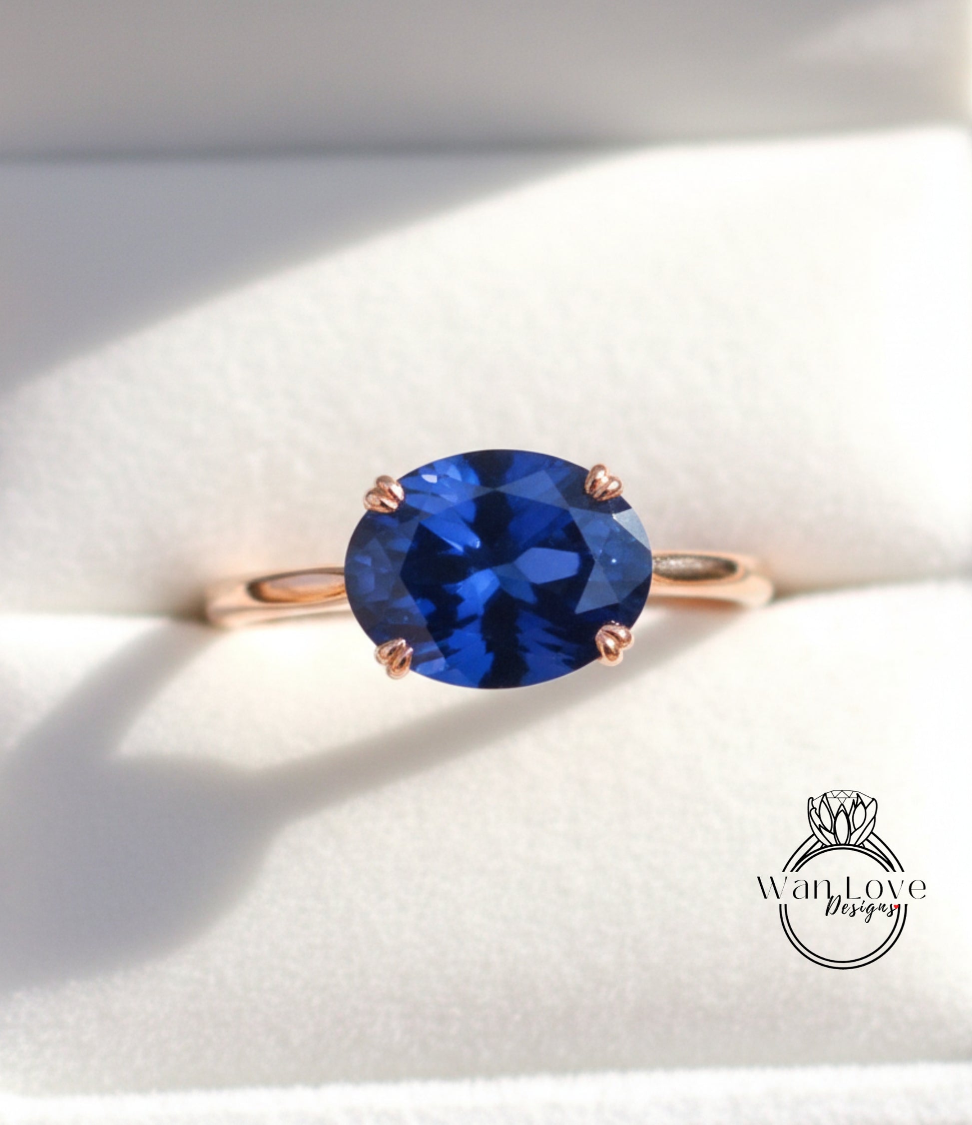 A close-up image of a gold ring with a large blue gemstone, placed on a white background.