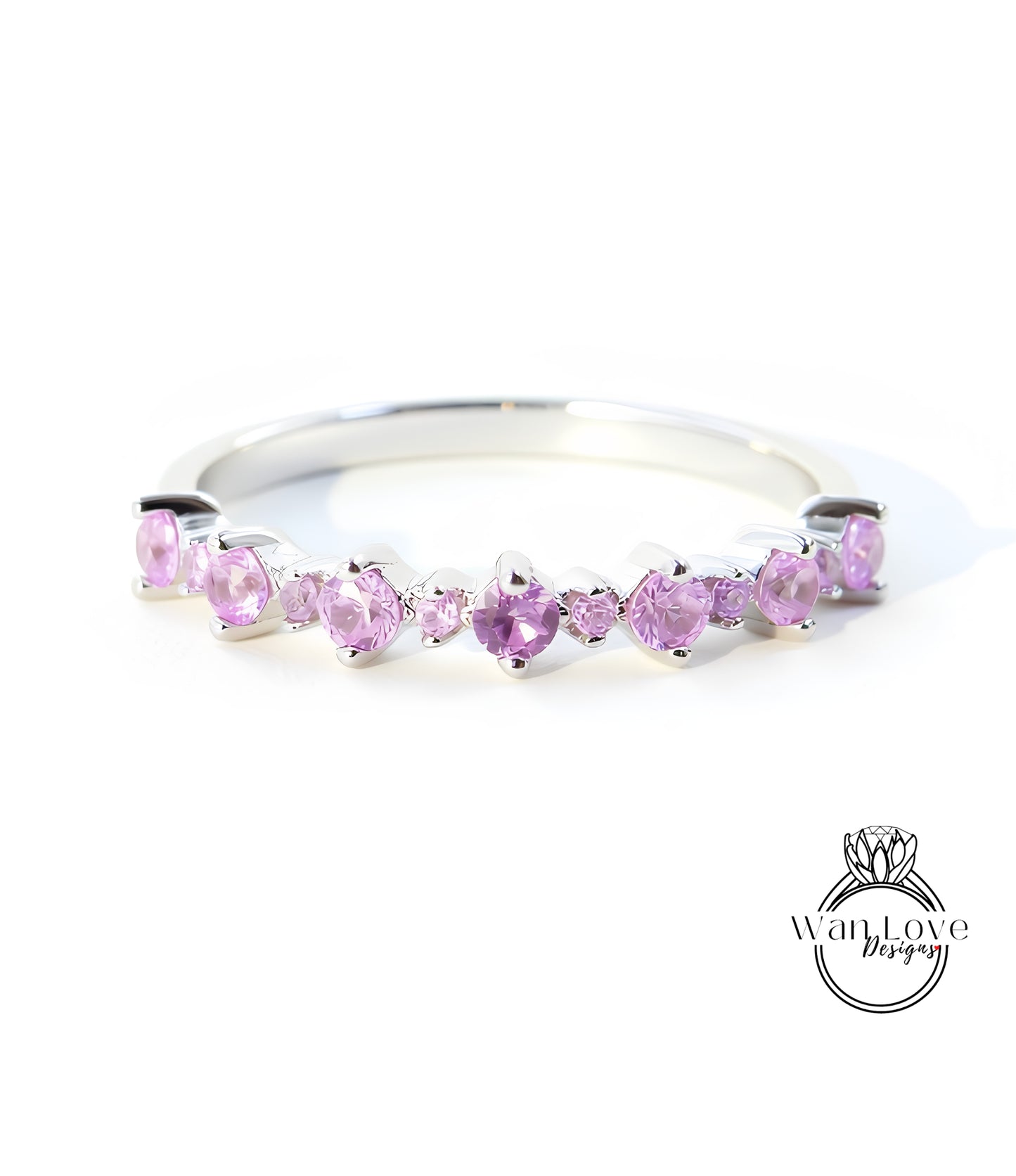 A silver ring with a row of pink gemstones, likely amethyst, set in a band.