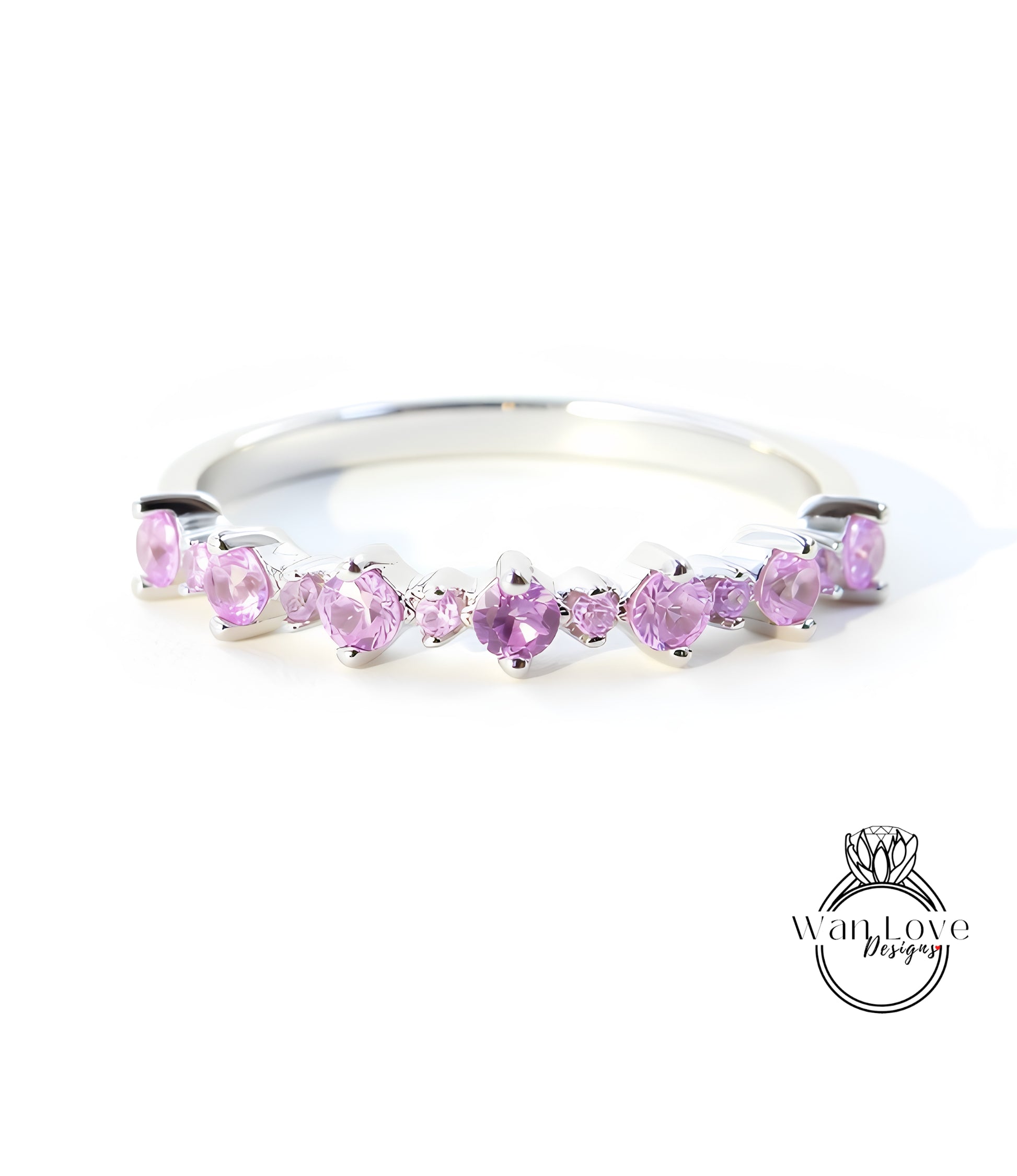 A silver ring with a row of pink gemstones, likely amethyst, set in a band.