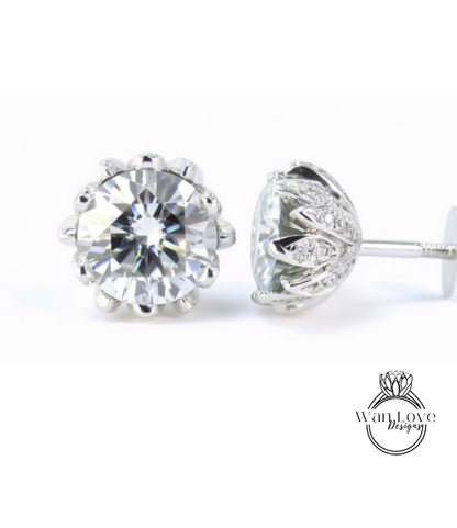 A pair of elegant diamond earrings with a large, brilliant-cut diamond set in a silver floral-designed earring back.