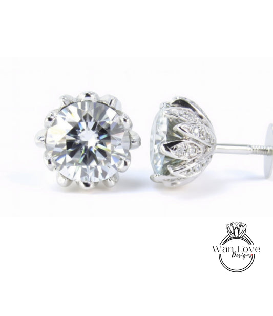 A pair of elegant diamond earrings with a large, brilliant-cut diamond set in a silver floral-designed earring back.