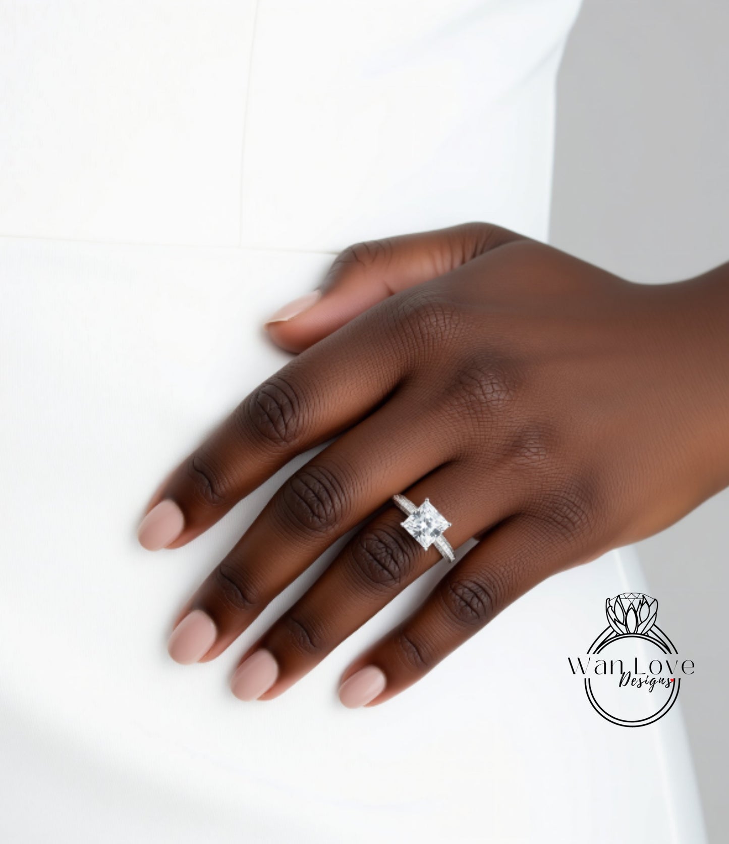 A close-up of a hand wearing a diamond engagement ring.