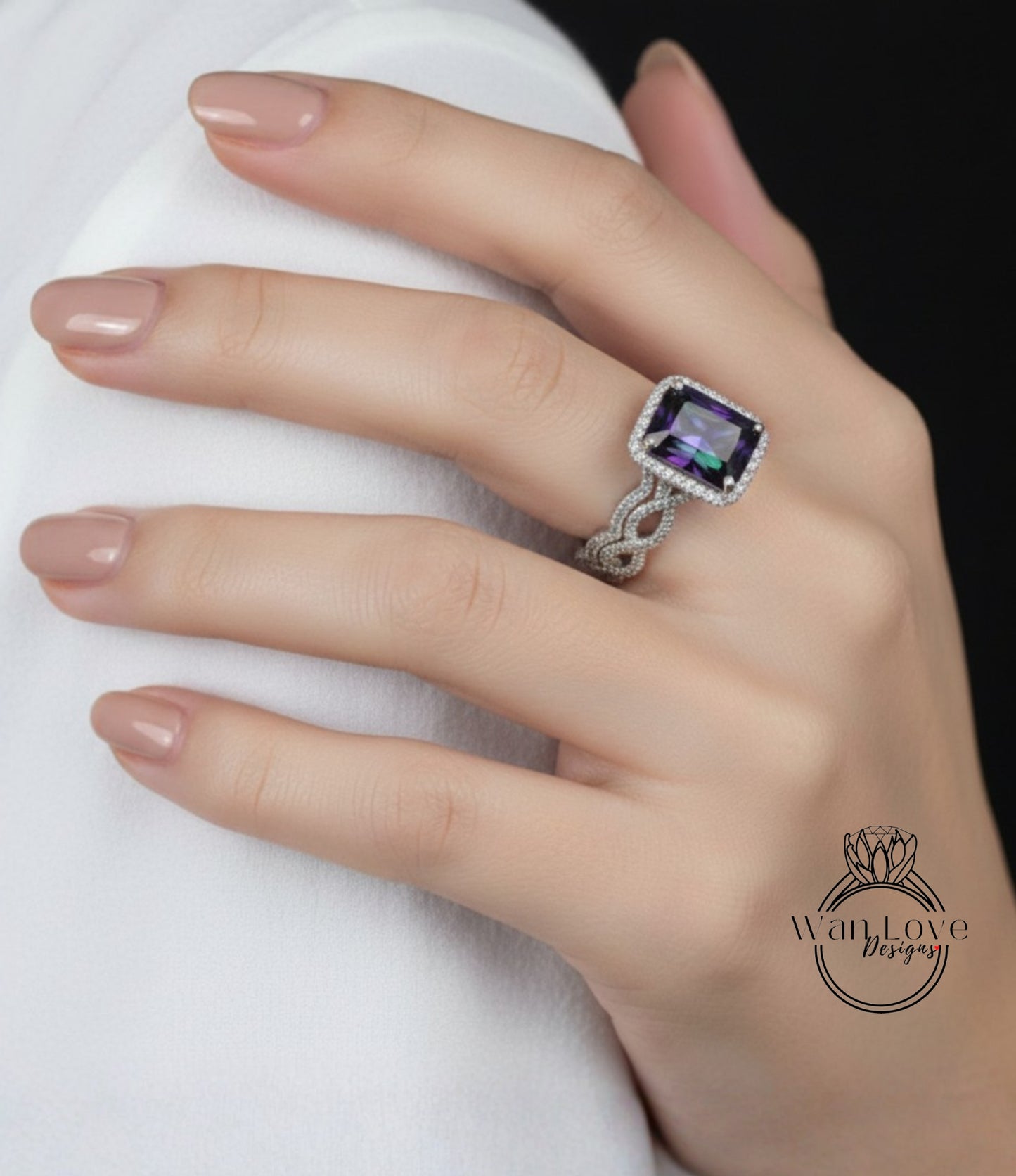A close-up of a hand wearing a ring with a large purple gemstone, resting on a white surface.