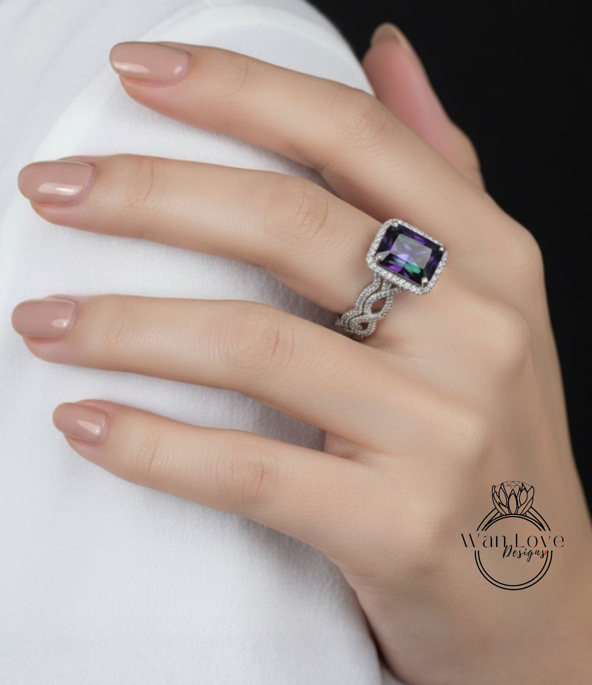 A close-up of a hand wearing a ring with a large purple gemstone, resting on a white surface.