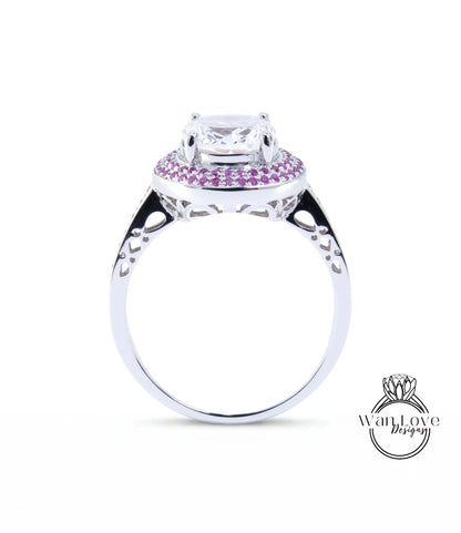 A silver ring with a large central gemstone surrounded by smaller gemstones, and a decorative band with a floral pattern.