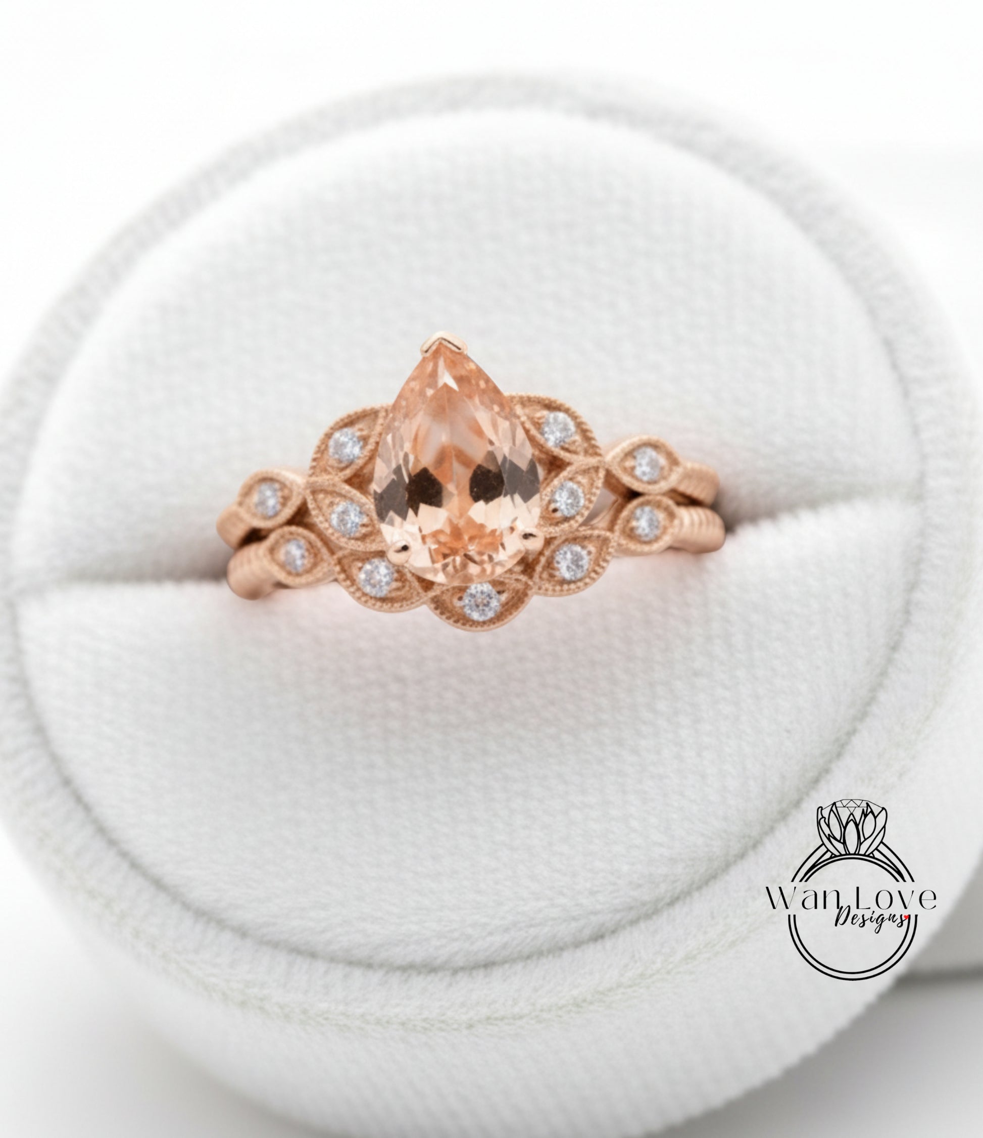 A gold ring with a large pear-shaped gemstone set in a floral design, displayed in a white jewelry box.