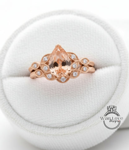 A gold ring with a large pear-shaped gemstone set in a floral design, displayed in a white jewelry box.