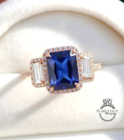 A close-up image of a beautiful blue gemstone ring with a large central blue gemstone surrounded by smaller diamonds and a halo of smaller diamonds around the edges.