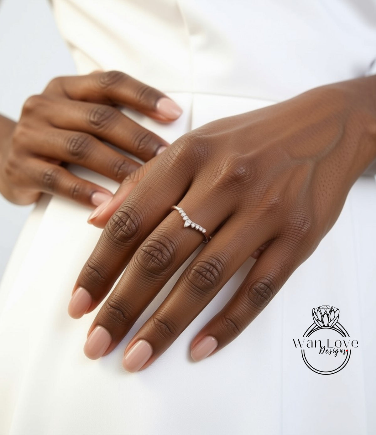 A close-up of a person's hand wearing a ring, with a white dress visible in the background.