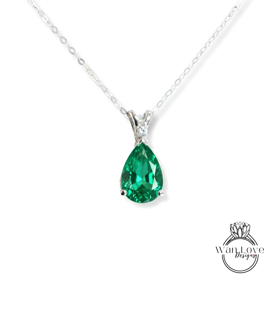 A silver necklace with a large, green gemstone pendant.