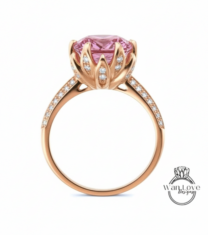 A gold ring with a large pink gemstone, likely a pink diamond, set in a decorative flower-like design.