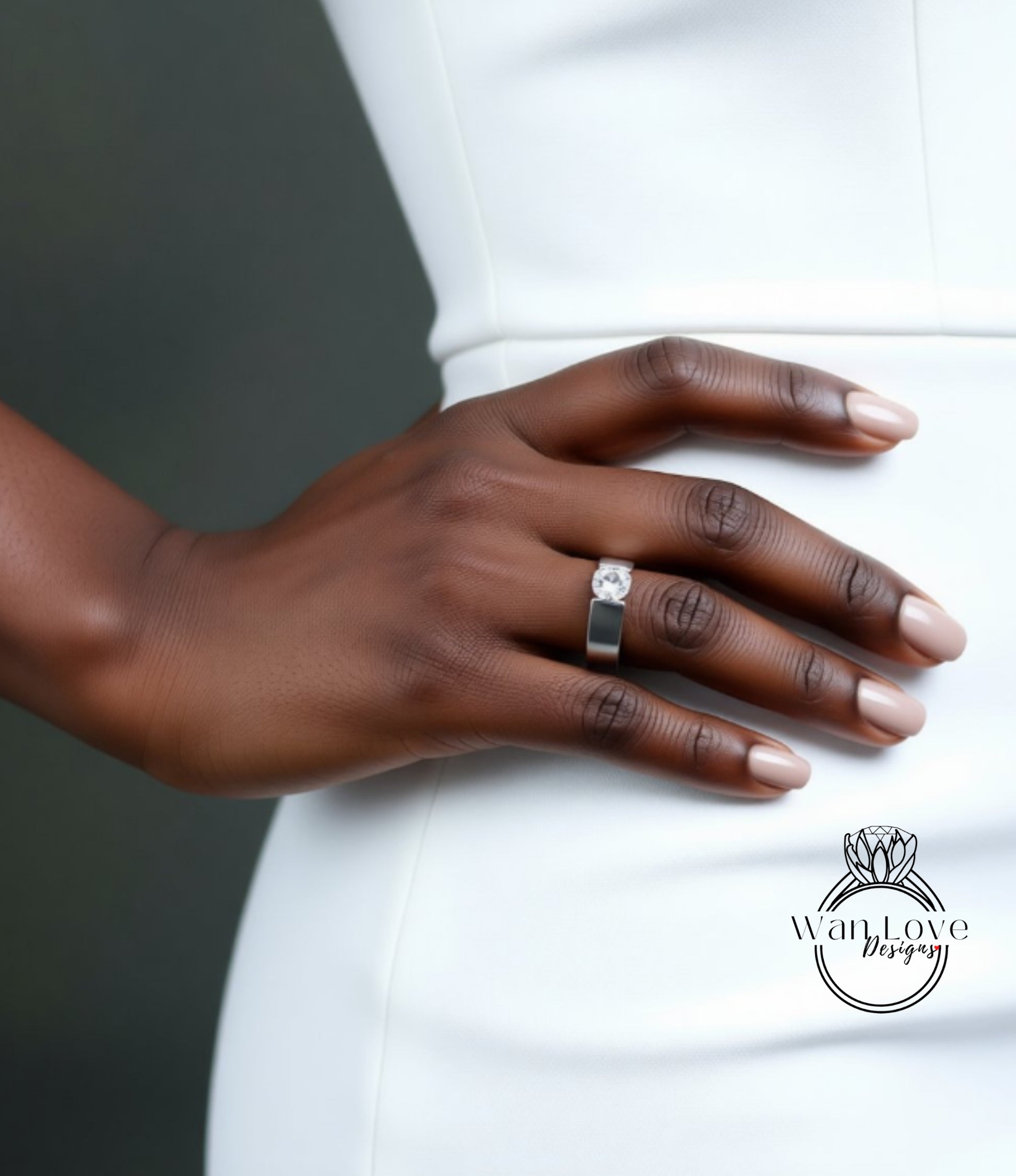 A close-up of a person's hand wearing a ring, with a white dress visible in the background.