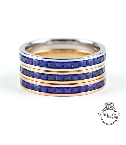 A ring with three concentric bands, each with a blue gemstone. The top and bottom bands are gold, while the middle band is silver. The gemstones are blue, and the ring appears to be made of metal.