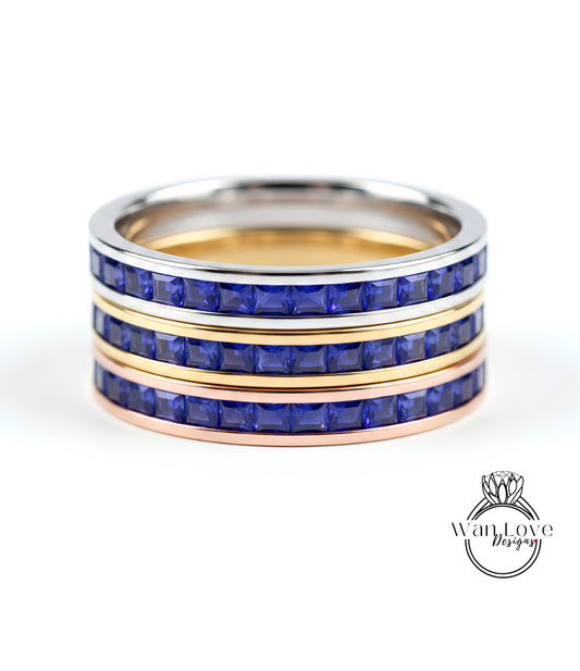A ring with three concentric bands, each with a blue gemstone. The top and bottom bands are gold, while the middle band is silver. The gemstones are blue, and the ring appears to be made of metal.