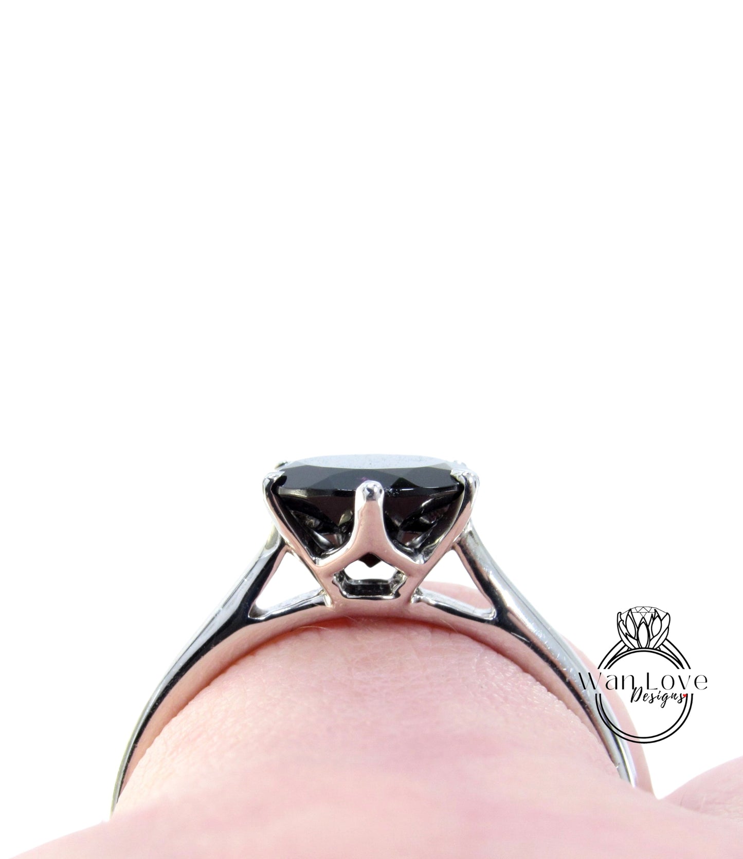 A close-up view of a silver engagement ring with a large black gemstone, set in a metal band.