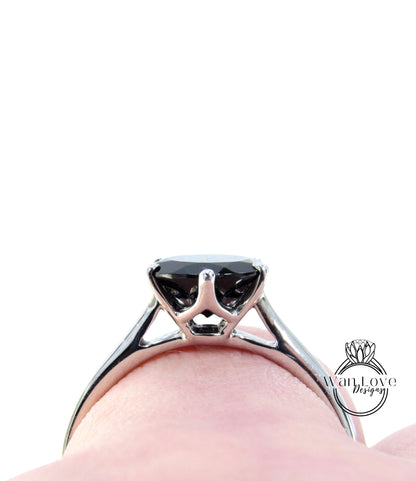 A close-up view of a silver engagement ring with a large black gemstone, set in a metal band.