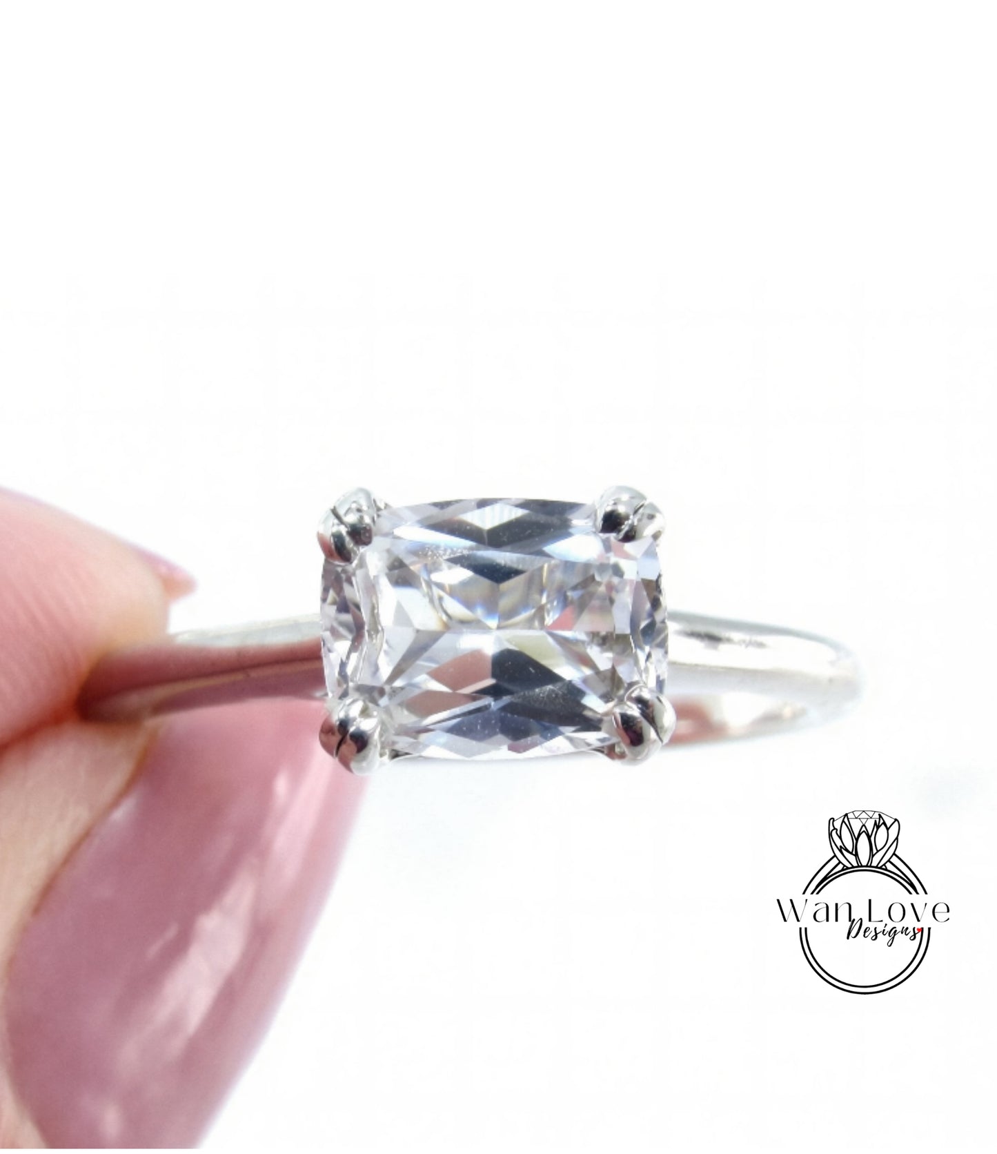 A close-up image of a diamond engagement ring being held in someone's hand.